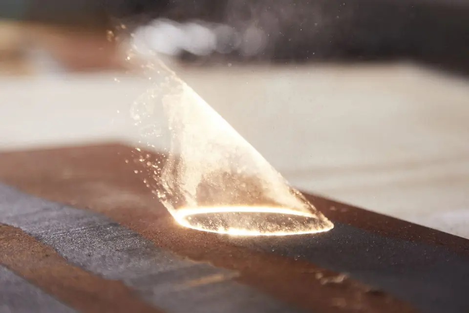 Fascicul laser care îndepărtează un strat de depuneri de pe o suprafață metalică
